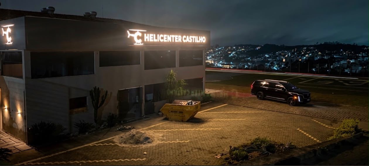 Cadillac Escalade no pátio do Helicenter Castilho à noite, com a cidade iluminada ao fundo